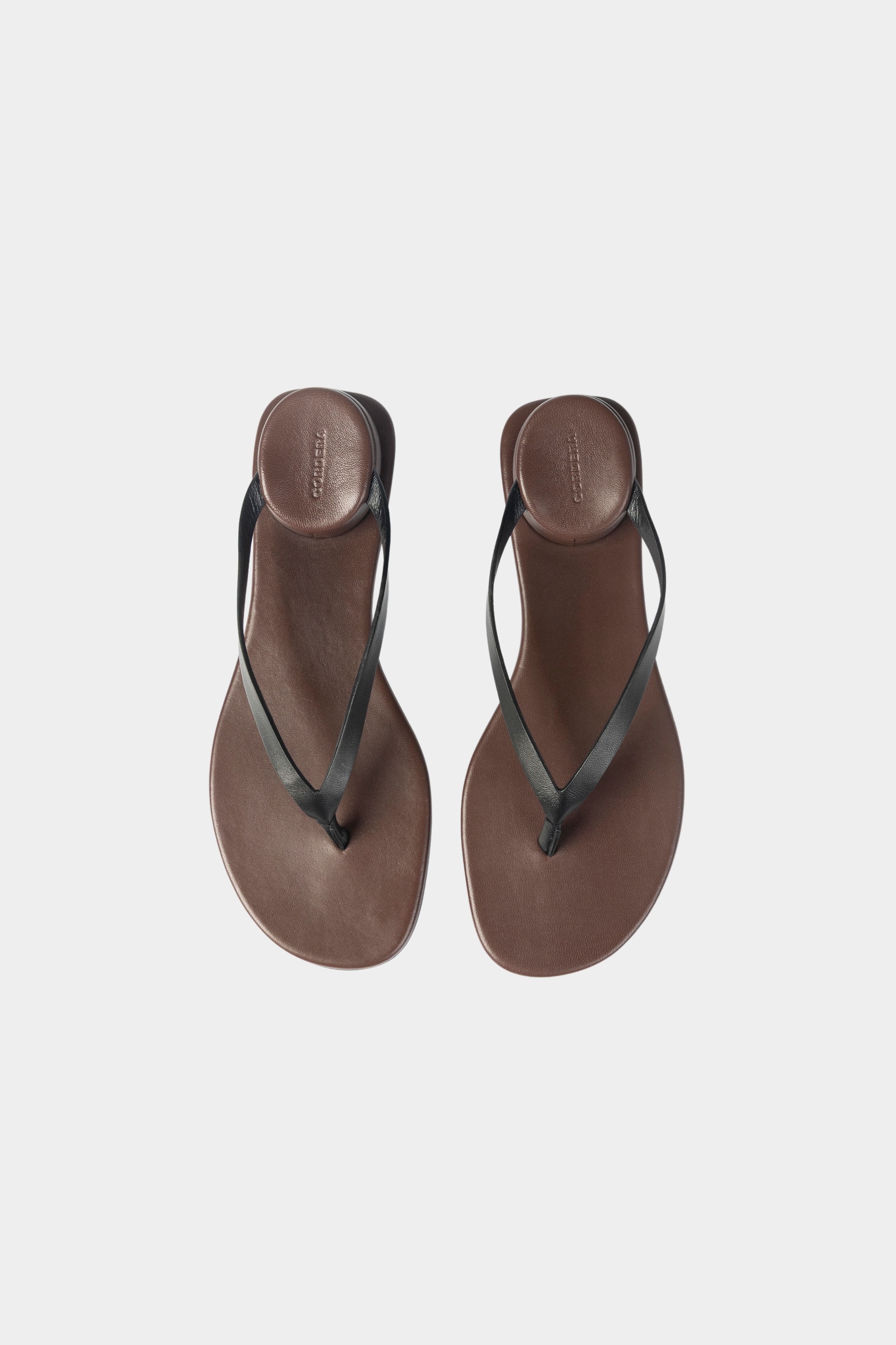 Black leather thong sandal with slim straps and padded brown footbed, top view
