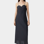 Black midi dress with heart-shaped neckline and slim straps, worn with flat sandals and fluid silhouette