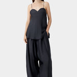 Black heart-shaped camisole with thin straps and relaxed silhouette, worn with wide leg trousers and sandals