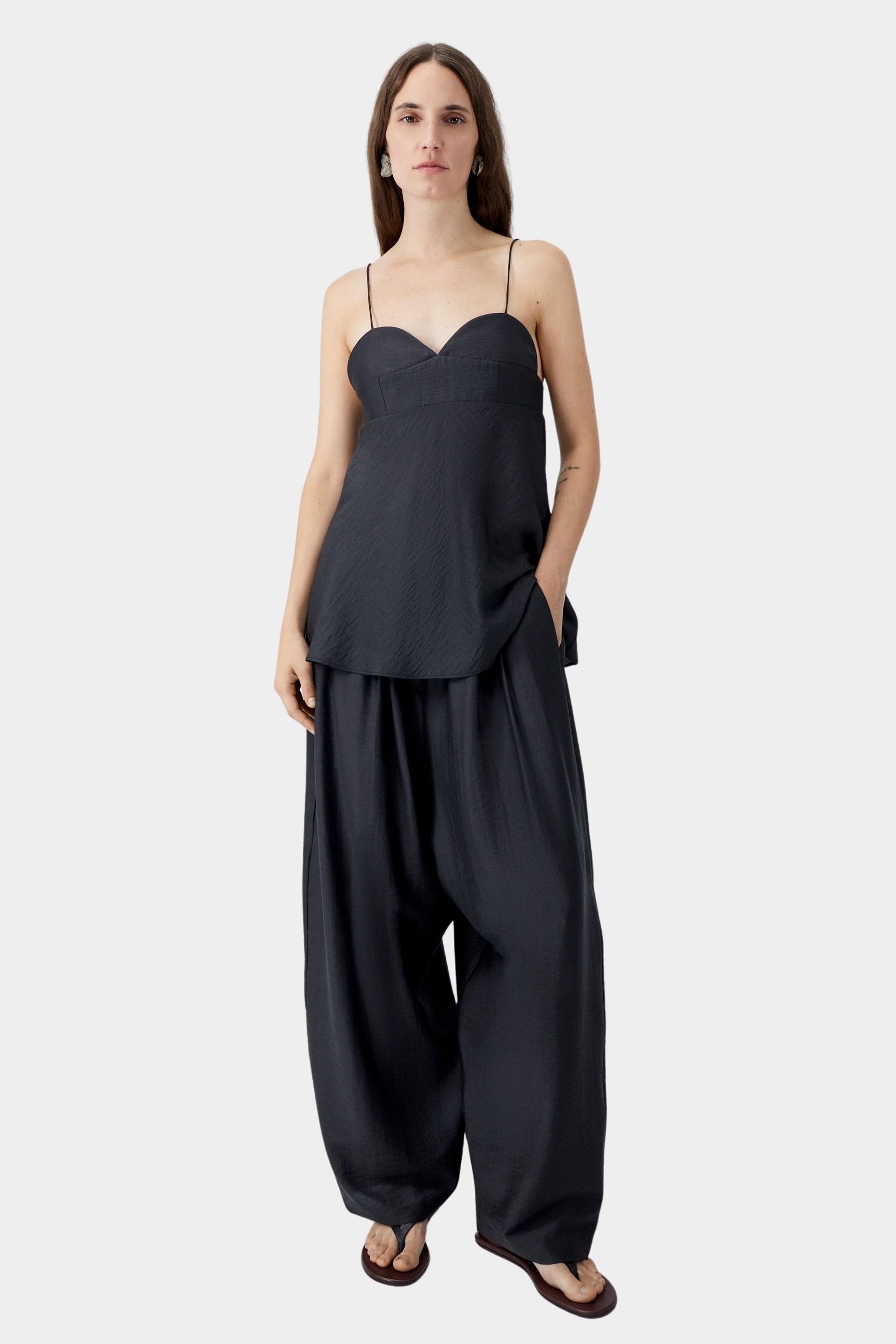 Black heart-shaped camisole with thin straps and relaxed silhouette, worn with wide leg trousers and sandals