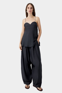 Black heart-shaped camisole with thin straps and relaxed silhouette, worn with wide leg trousers and sandals