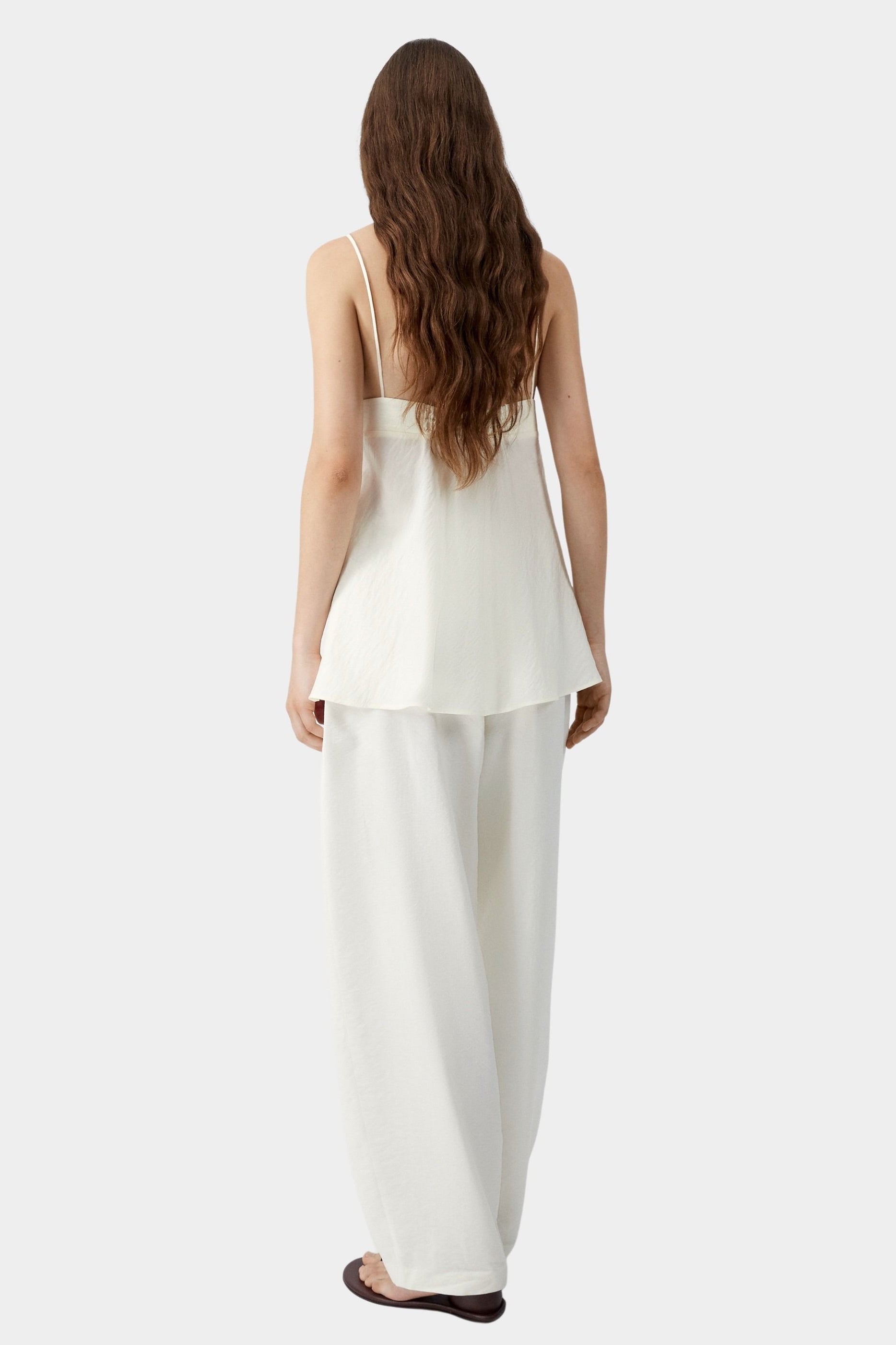Cream camisole top with thin straps, soft back drape, and relaxed silhouette