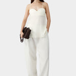 Cream heart-shaped camisole with thin straps and relaxed silhouette, worn with matching wide leg pants and sandals