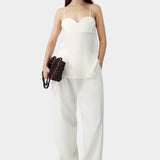 Cream heart-shaped camisole with thin straps and relaxed silhouette, worn with matching wide leg pants and sandals