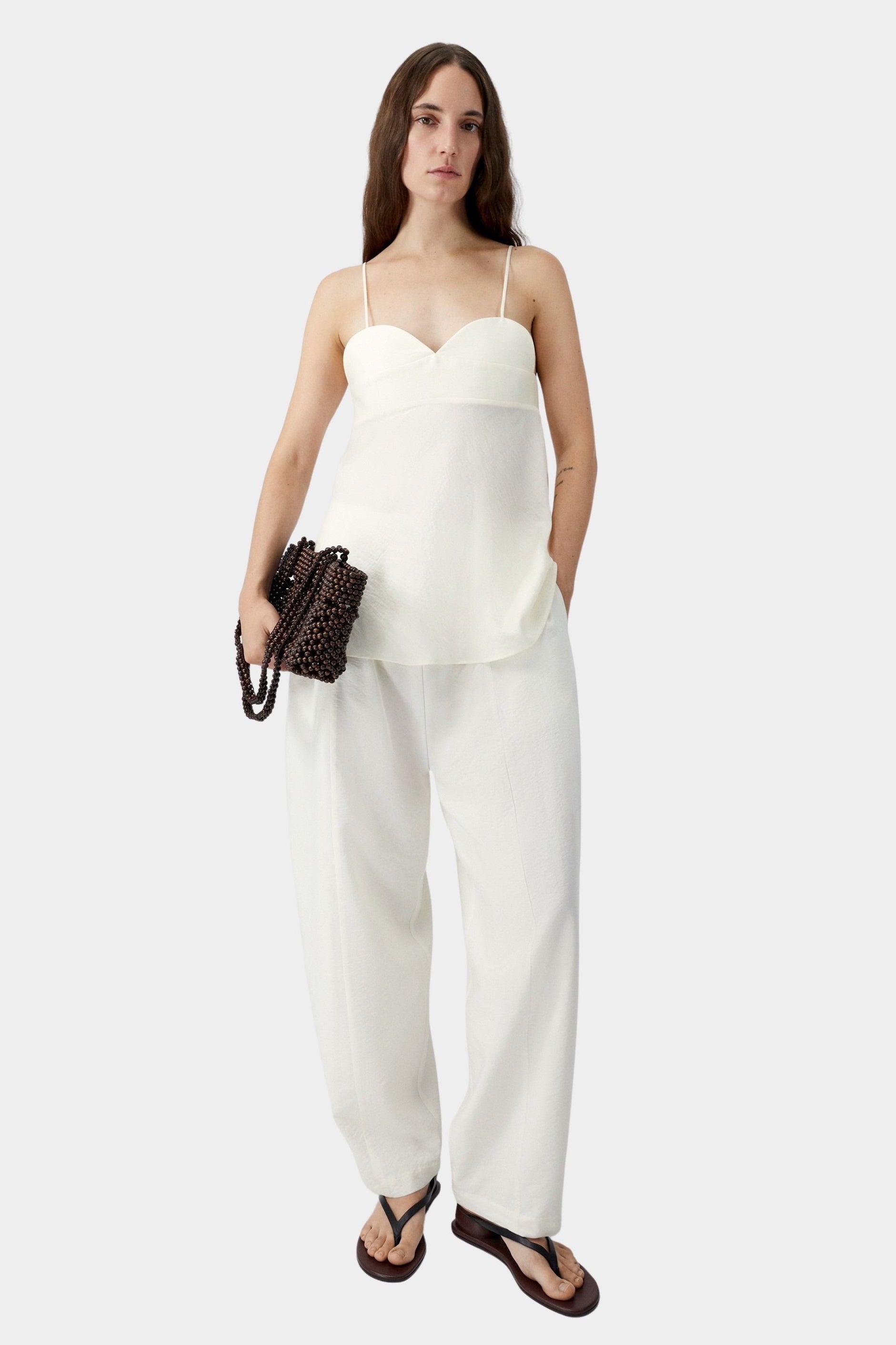Cream heart-shaped camisole with thin straps and relaxed silhouette, worn with matching wide leg pants and sandals