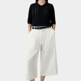 Black lace panel polo top worn with white wide leg trousers and black flats