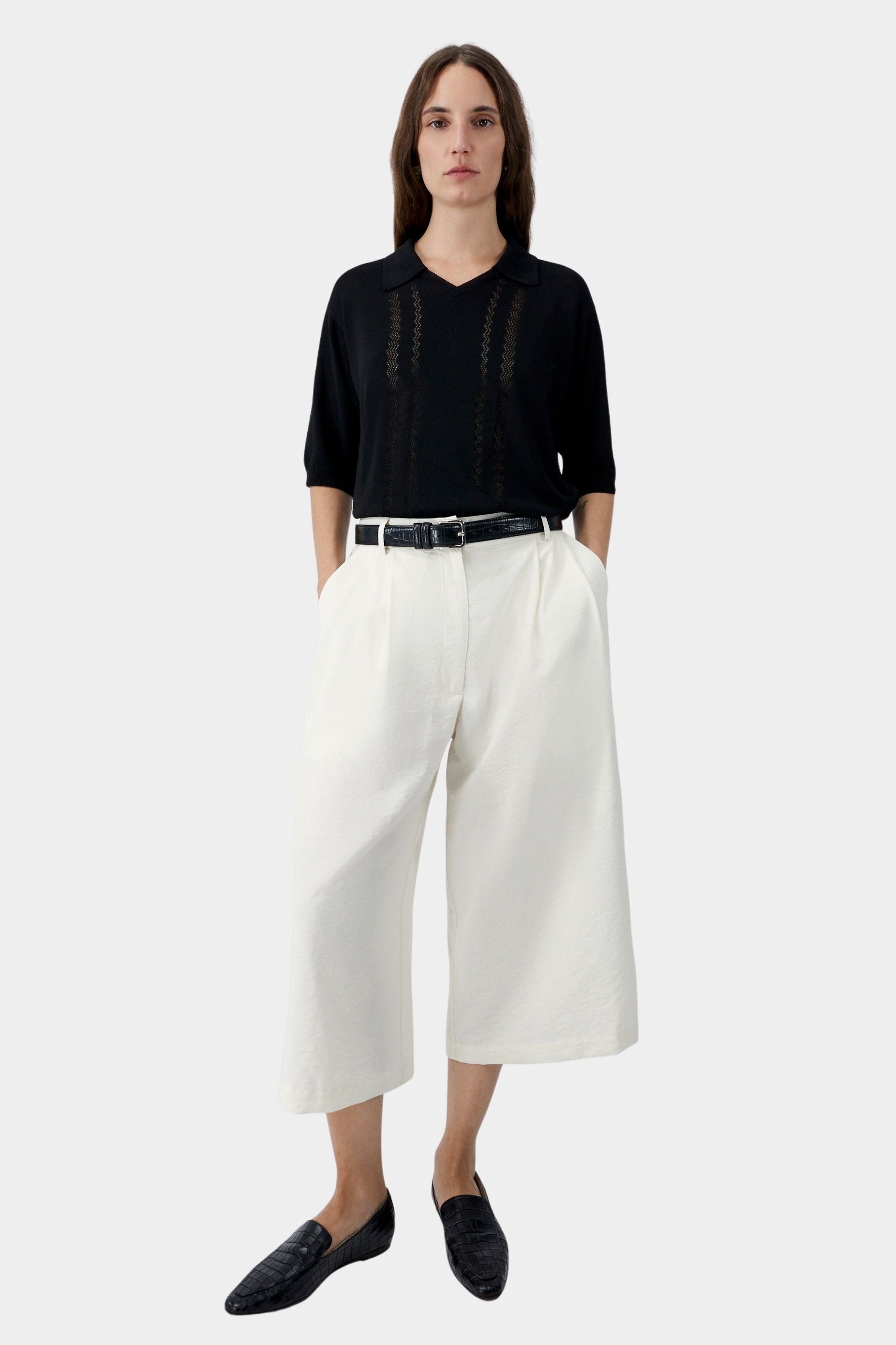 Black lace panel polo top worn with white wide leg trousers and black flats