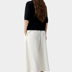 Black short sleeve knit polo with relaxed fit and clean back, worn with light trousers