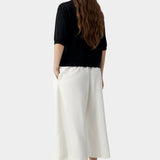 Black short sleeve knit polo with relaxed fit and clean back, worn with light trousers