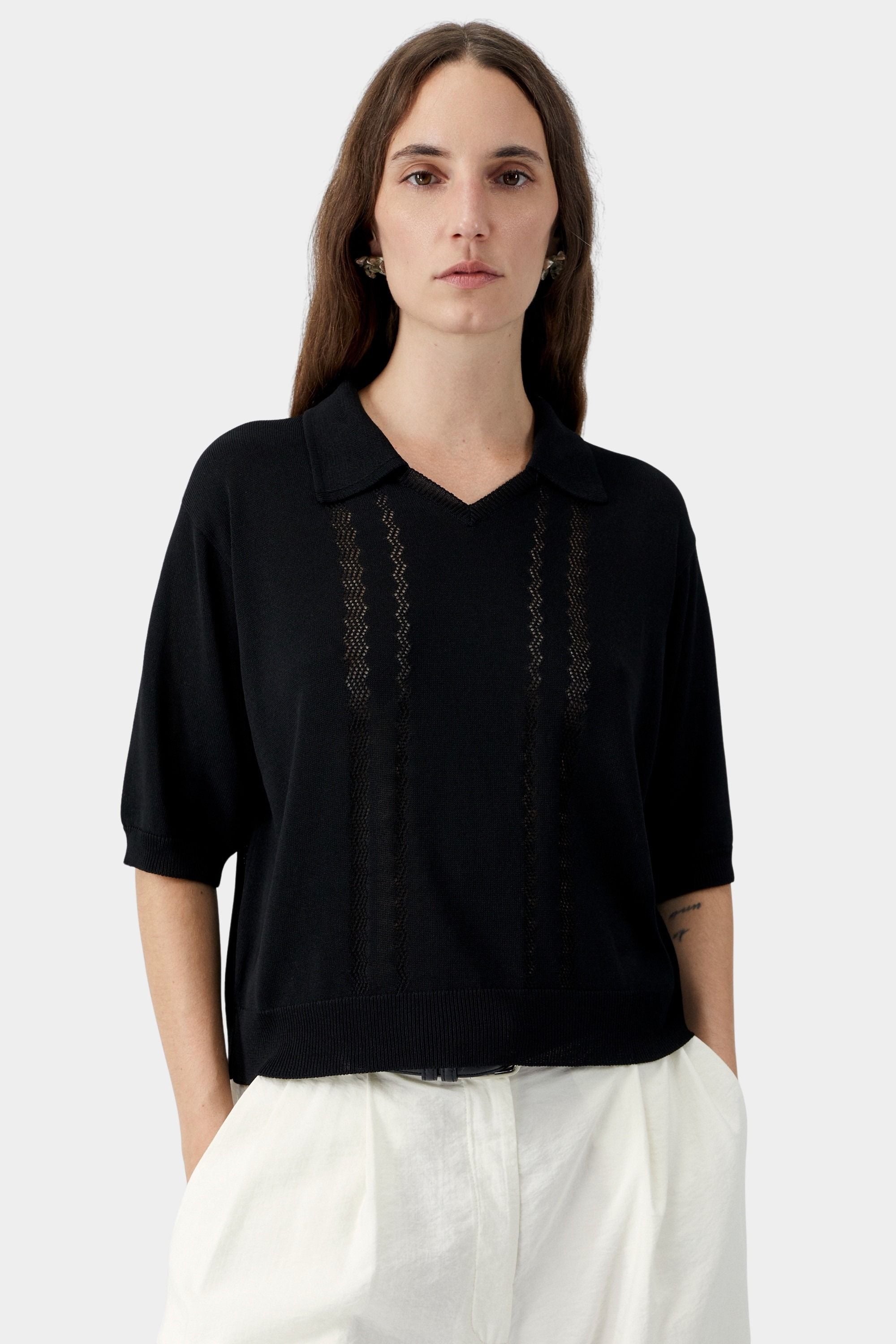 Black knit polo top with collar, V neckline, and sheer vertical lace panel detailing