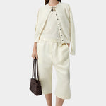 Cream flecked knit cardigan worn open with matching skirt and sandals