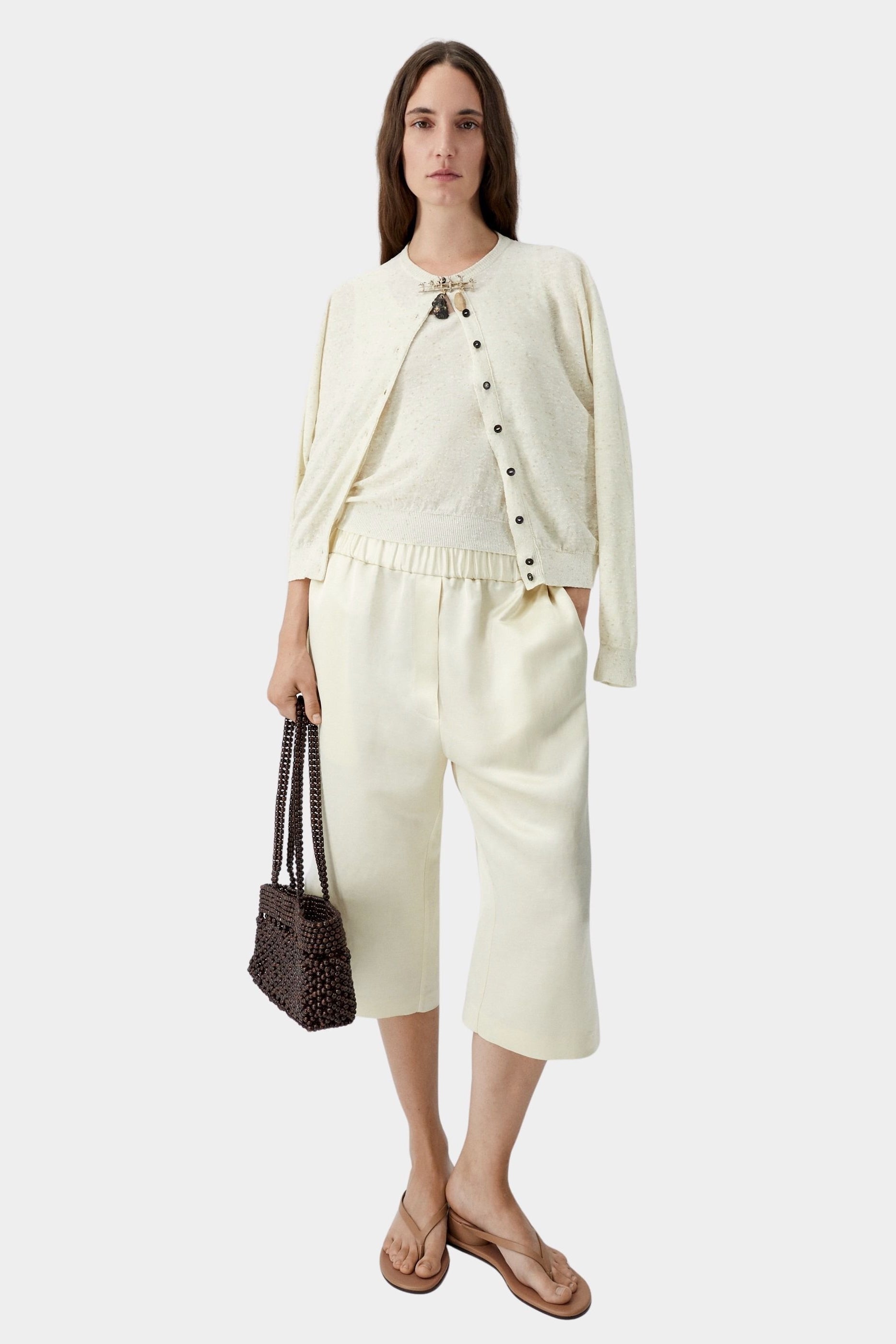 Cream flecked knit cardigan worn open with matching skirt and sandals