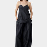 Black wide leg maxi pants with elastic waist and fluid drape, worn with black camisole and sand