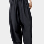 Black wide leg pants with elastic waist and drawstring detail, showing soft volume and drape