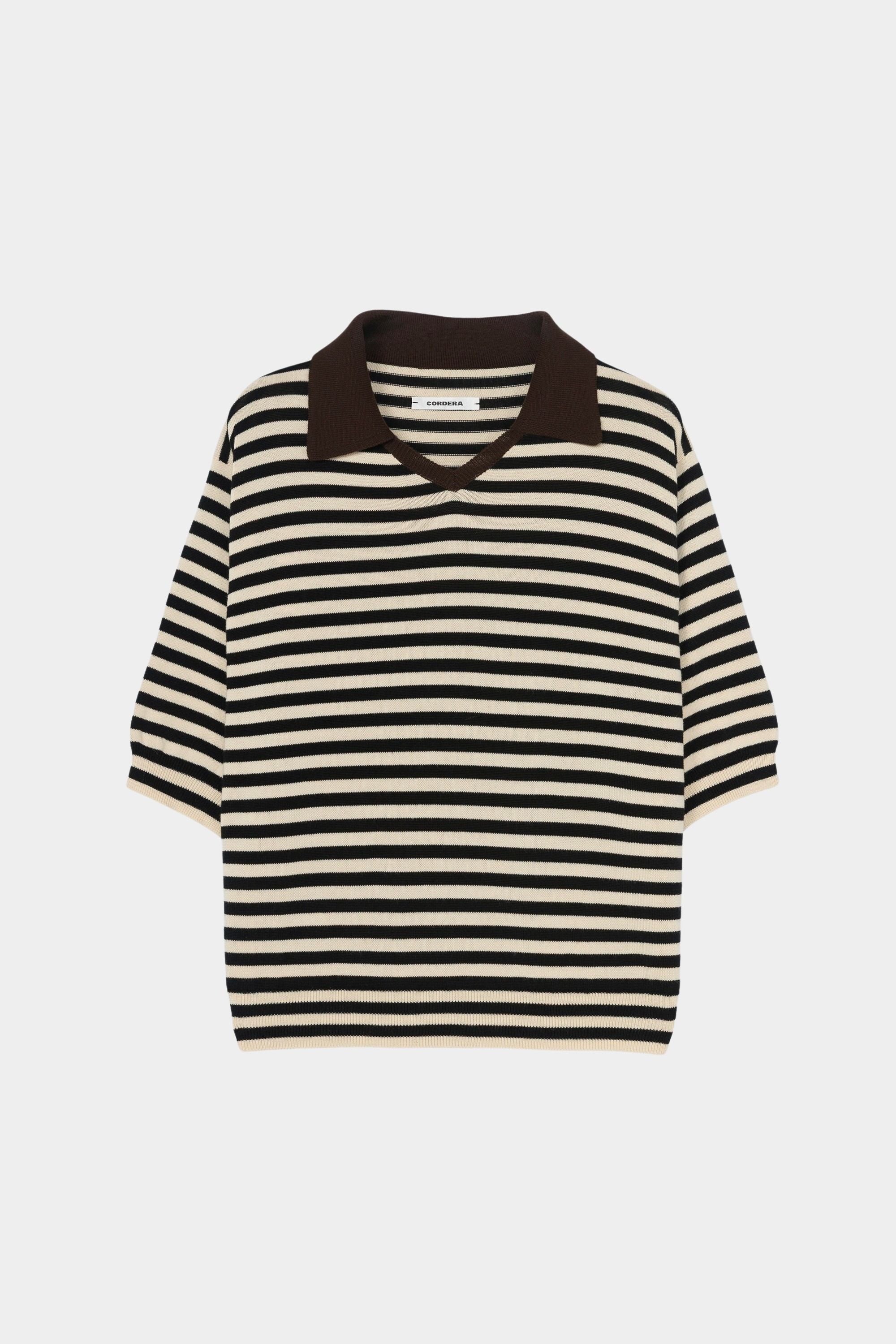 Cordera organic cotton V-neck polo in black and cream stripe, flat lay highlighting boxy silhouette, ribbed hem, and short sleeves