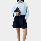Light blue oversized shirt worn with tailored black shorts and sandals