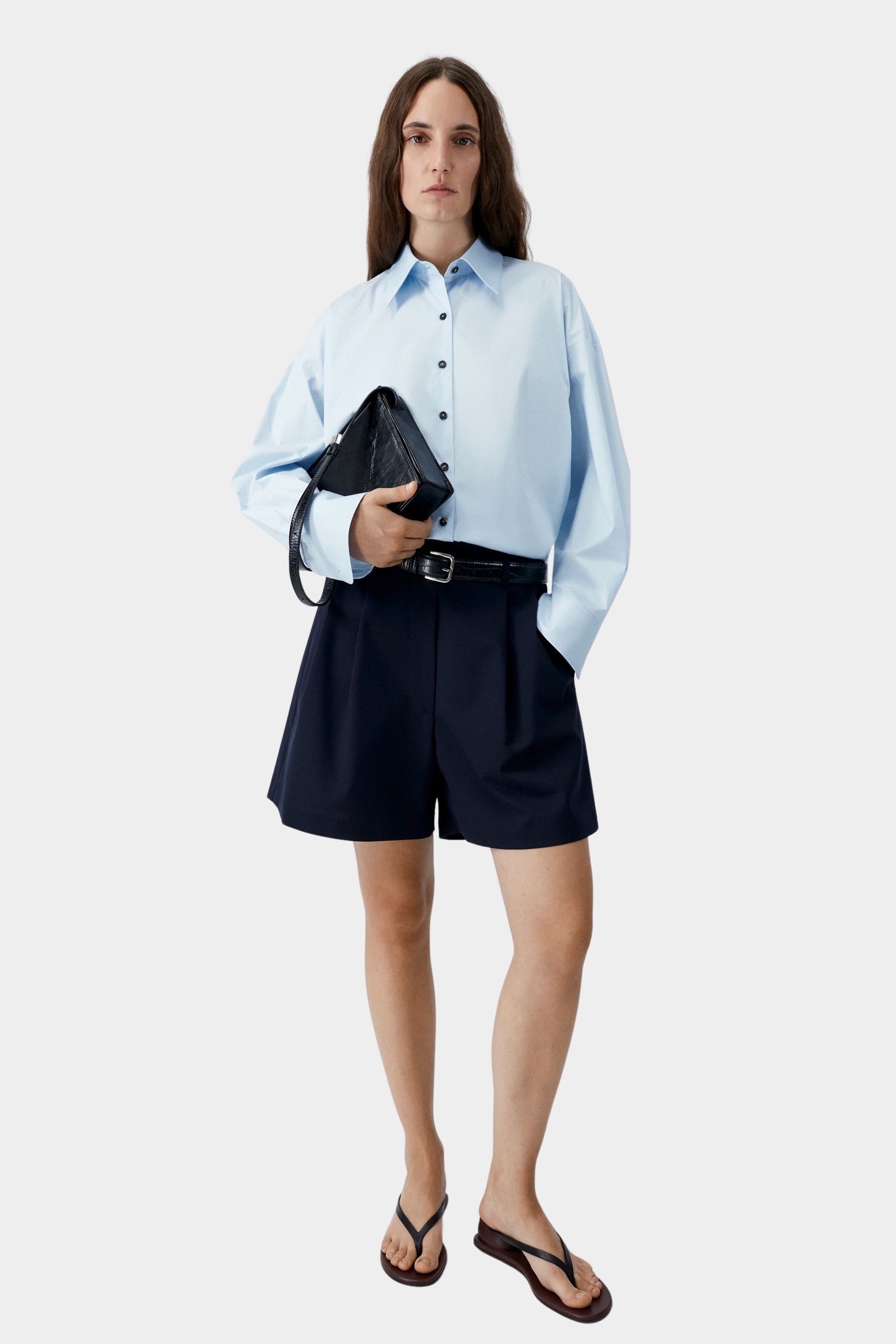 Light blue oversized shirt worn with tailored black shorts and sandals