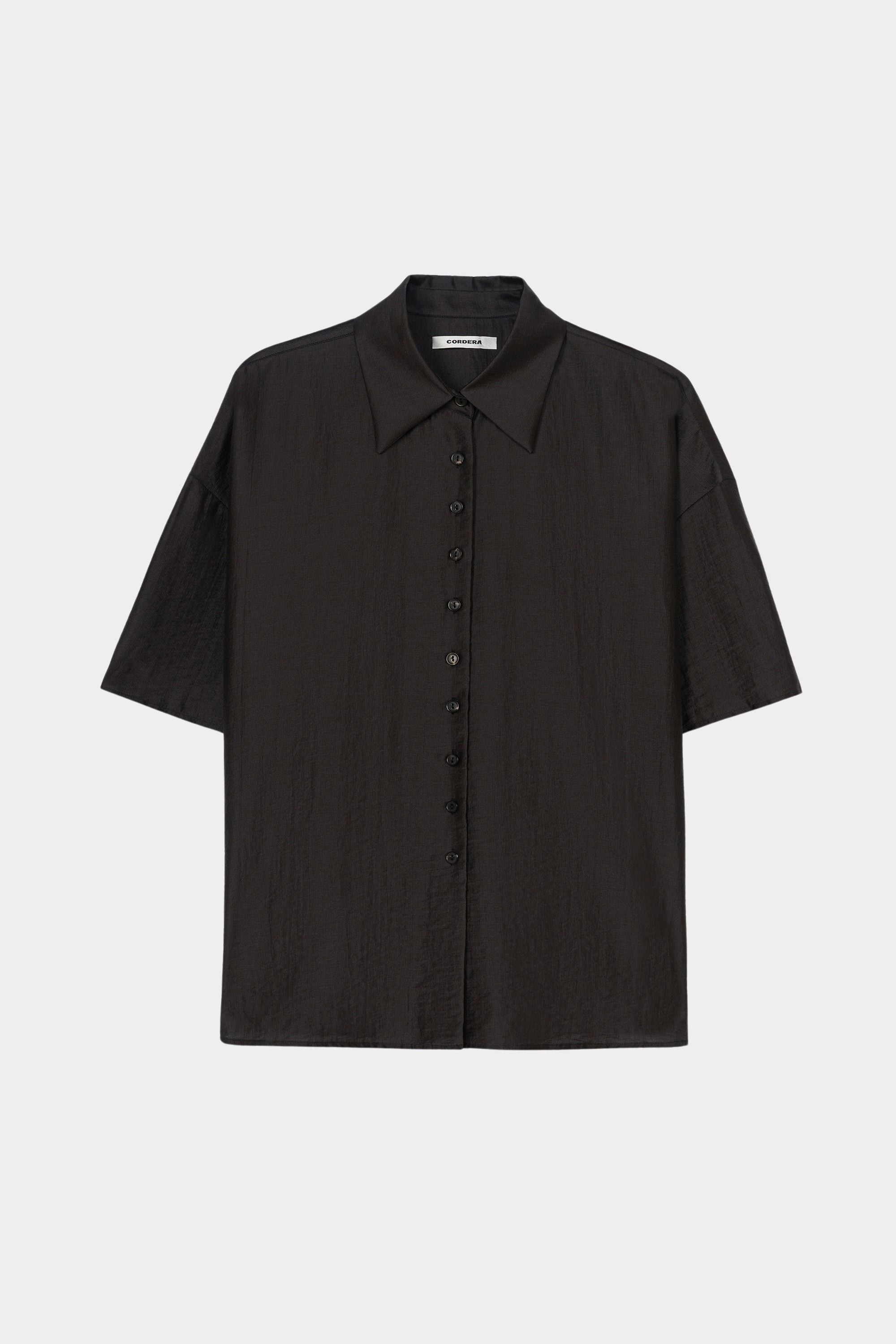 Black short sleeve button-up shirt with pointed collar, boxy silhouette, and lightweight textured fabric