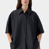 Black oversized short sleeve blouse with button closure, pointed collar, and soft drape detail