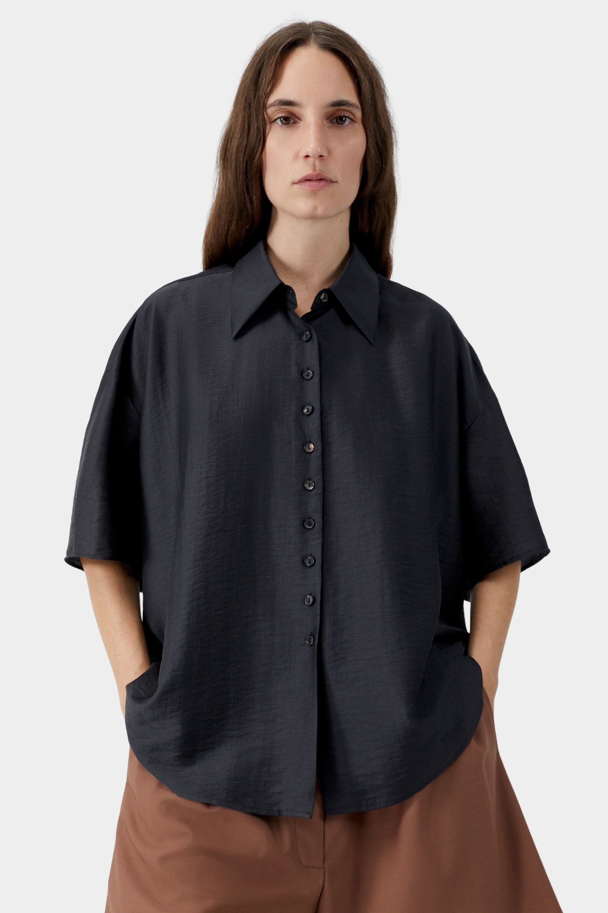 Black oversized short sleeve blouse with button closure, pointed collar, and soft drape detail