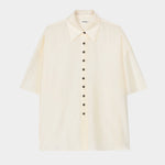 Cream short sleeve button-up shirt with pointed collar, boxy silhouette, and lightweight textured fabric