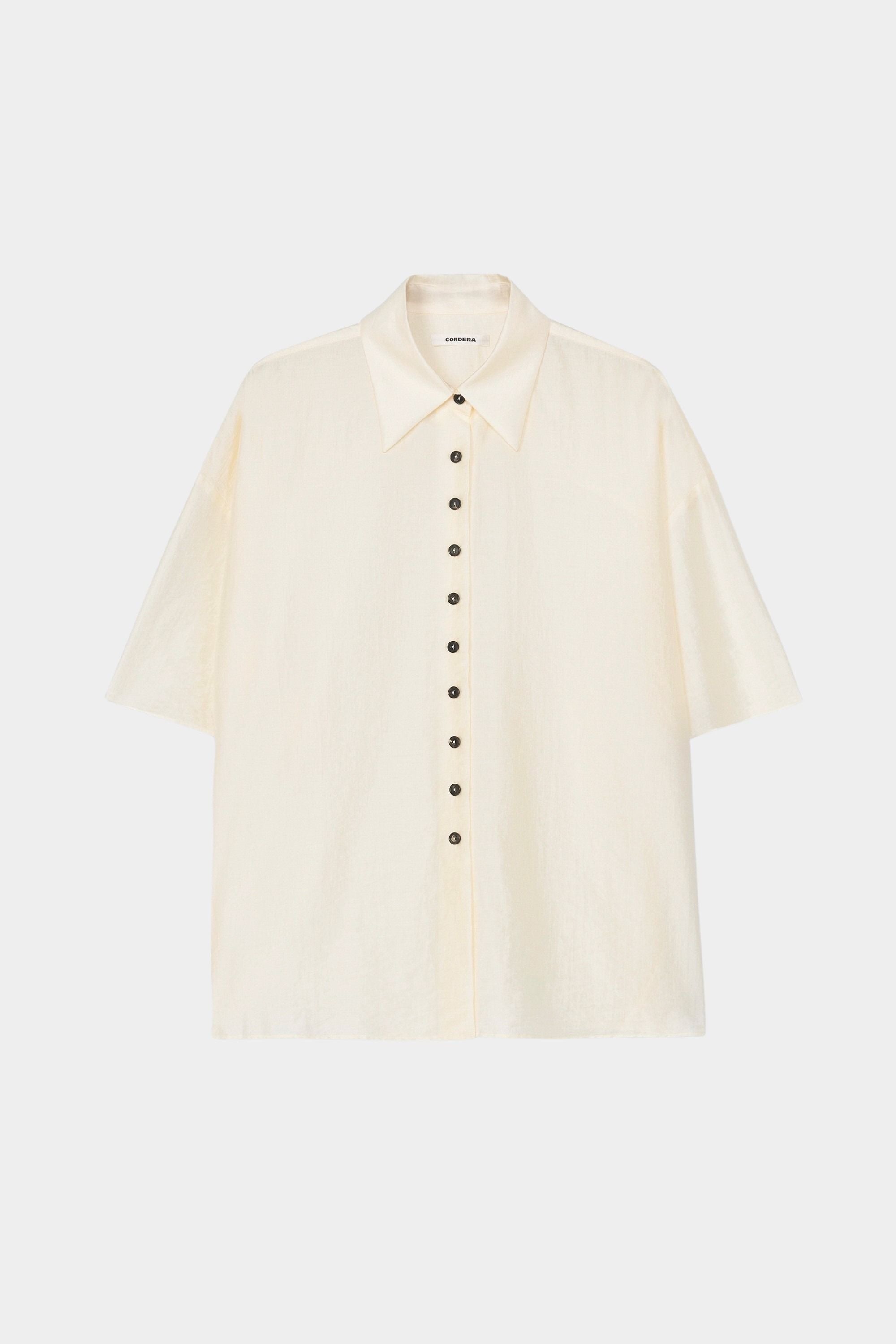 Cream short sleeve button-up shirt with pointed collar, boxy silhouette, and lightweight textured fabric