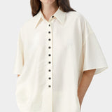 Cream short sleeve blouse with button closure, pointed collar, and soft airy texture detail