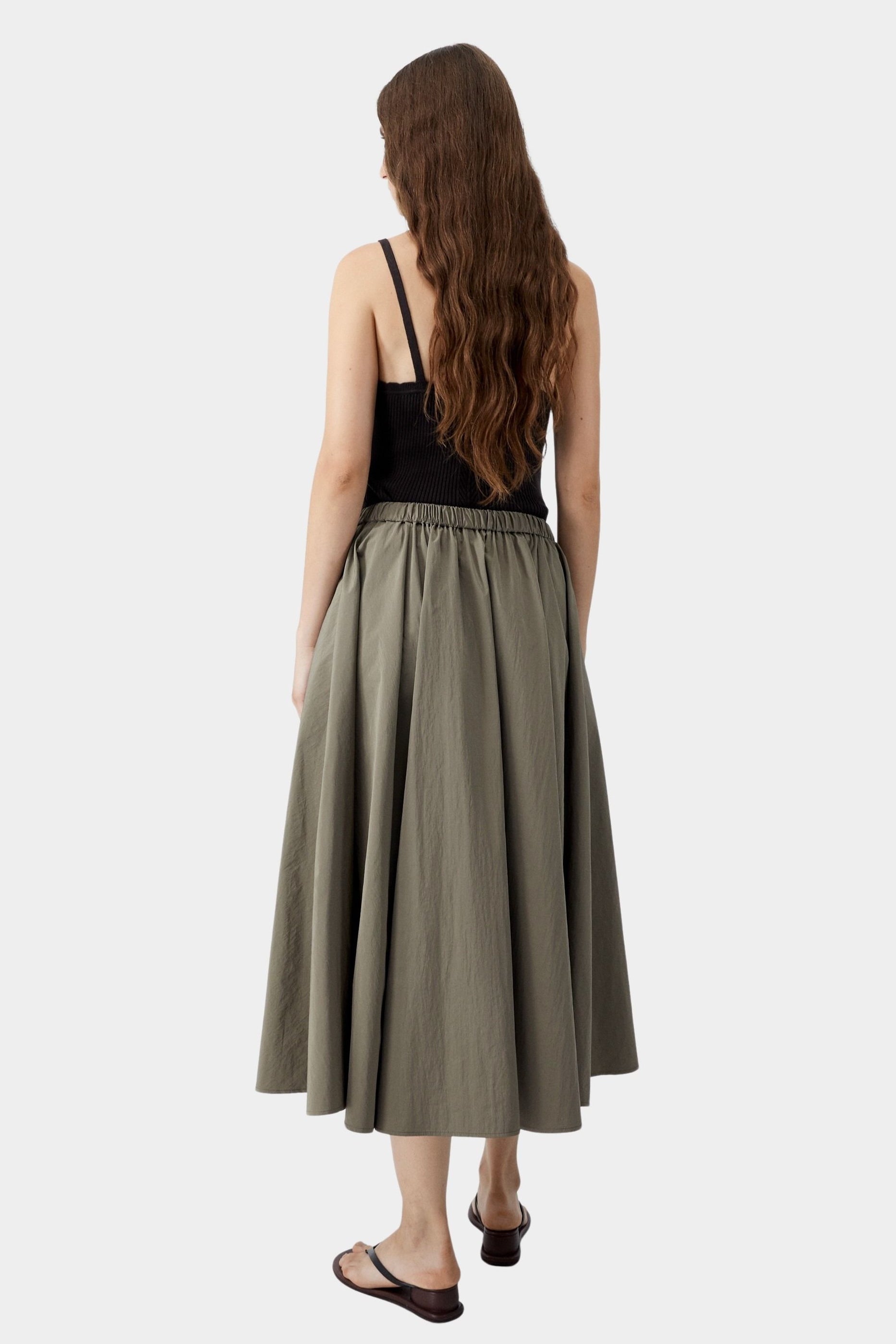 Vetiver green midi skirt in lightweight cotton with full silhouette and elastic waistband, worn from back