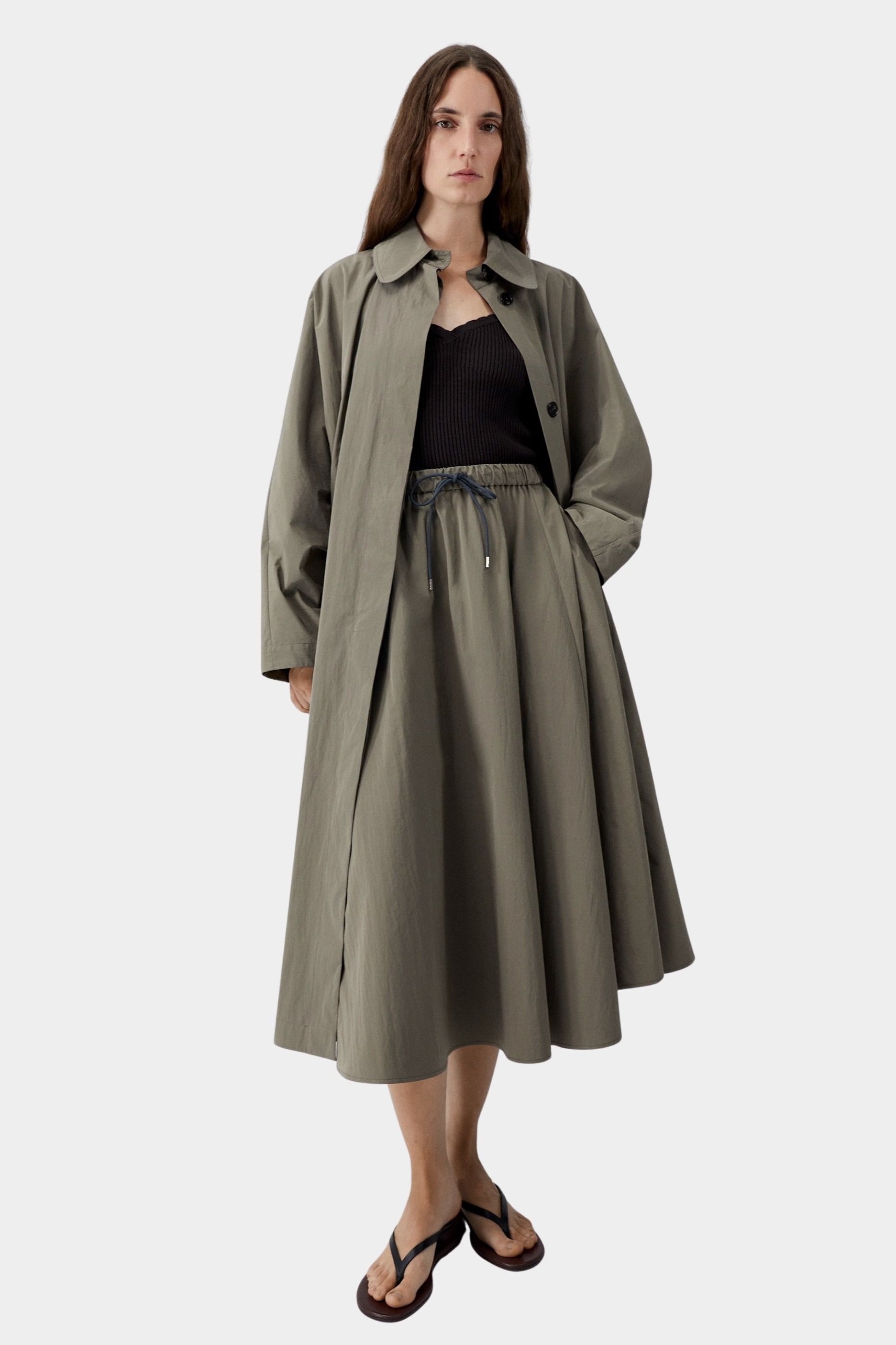 Vetiver green cotton technical midi skirt with elastic waist and drawstring, worn with black ribbed tank and sandals