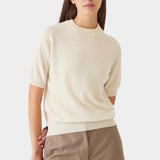 Model wearing the ivory DEMYLEE Irelia cashmere top with short raglan sleeves and taupe trousers