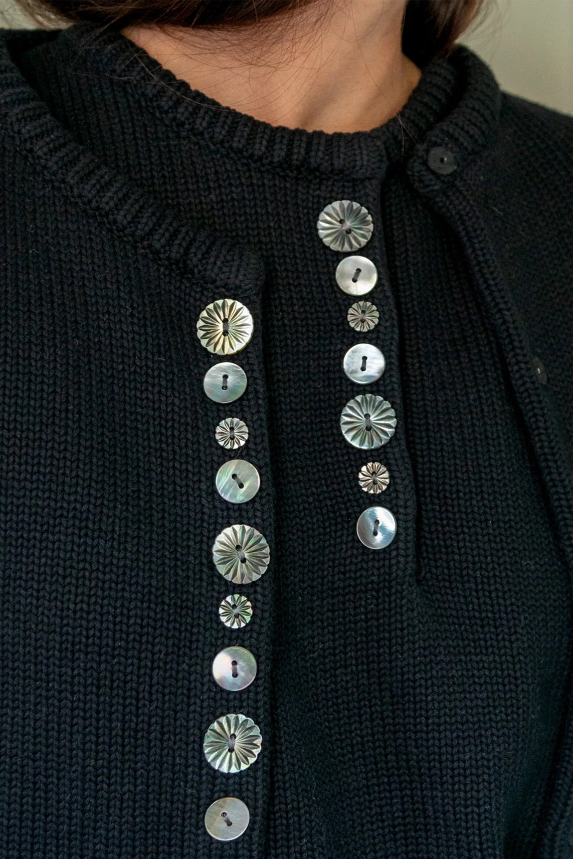 Close view of carved shell buttons on the black DEMYLEE Soleil cotton cardigan