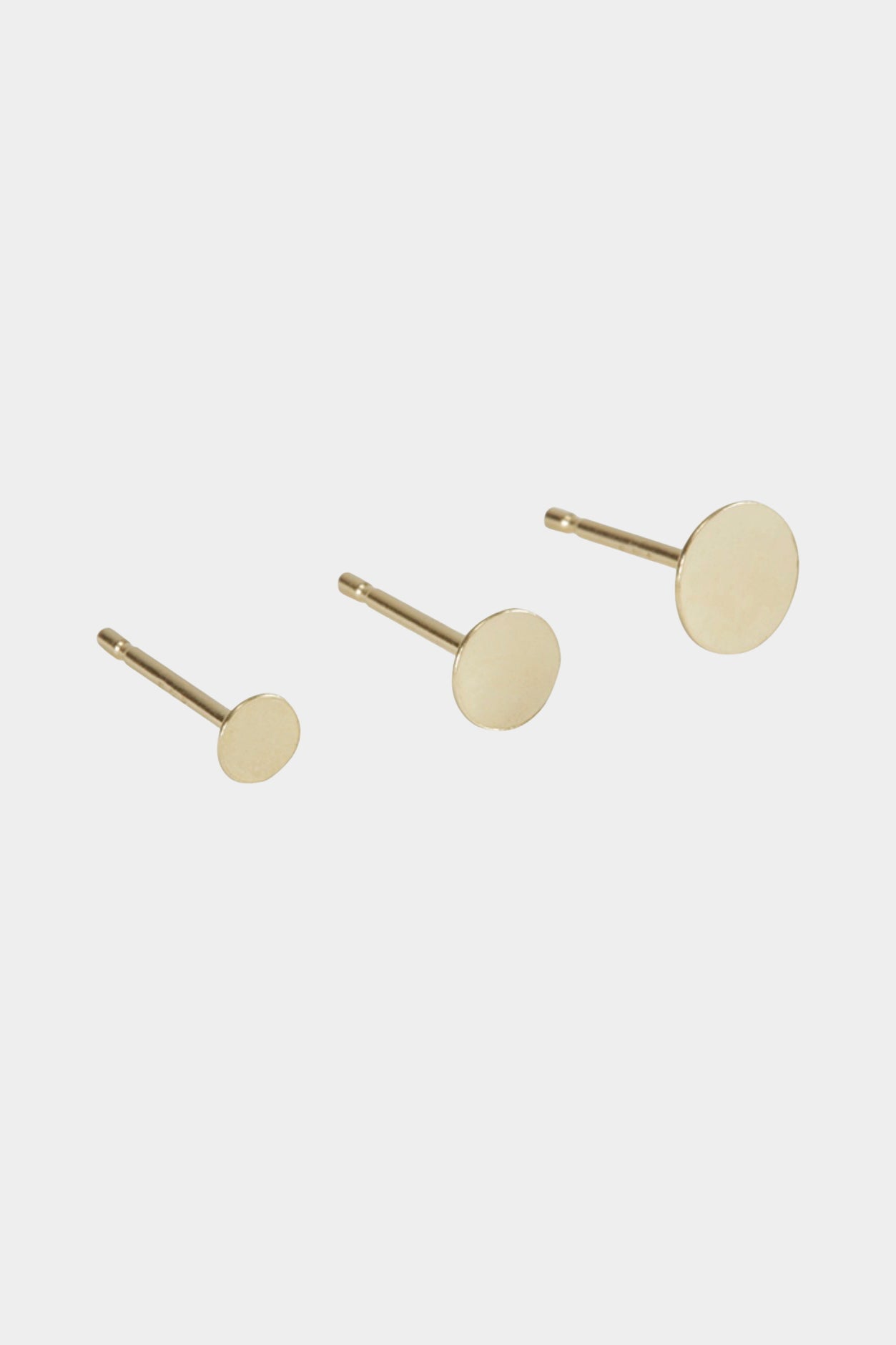 Gold disc stud earrings shown in assorted sizes for layering and stacking.
