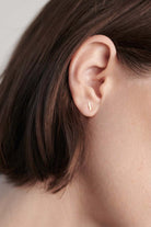 Model wearing 14K gold T-bar stud earring styled for everyday wear.