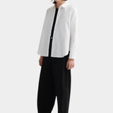 Kowtow Daily Shirt in white worn open over black top with wide leg trousers, full length view