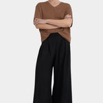 Front view of a model wearing the black Kowtow Drape Pant with a brown tee and white sneakers.