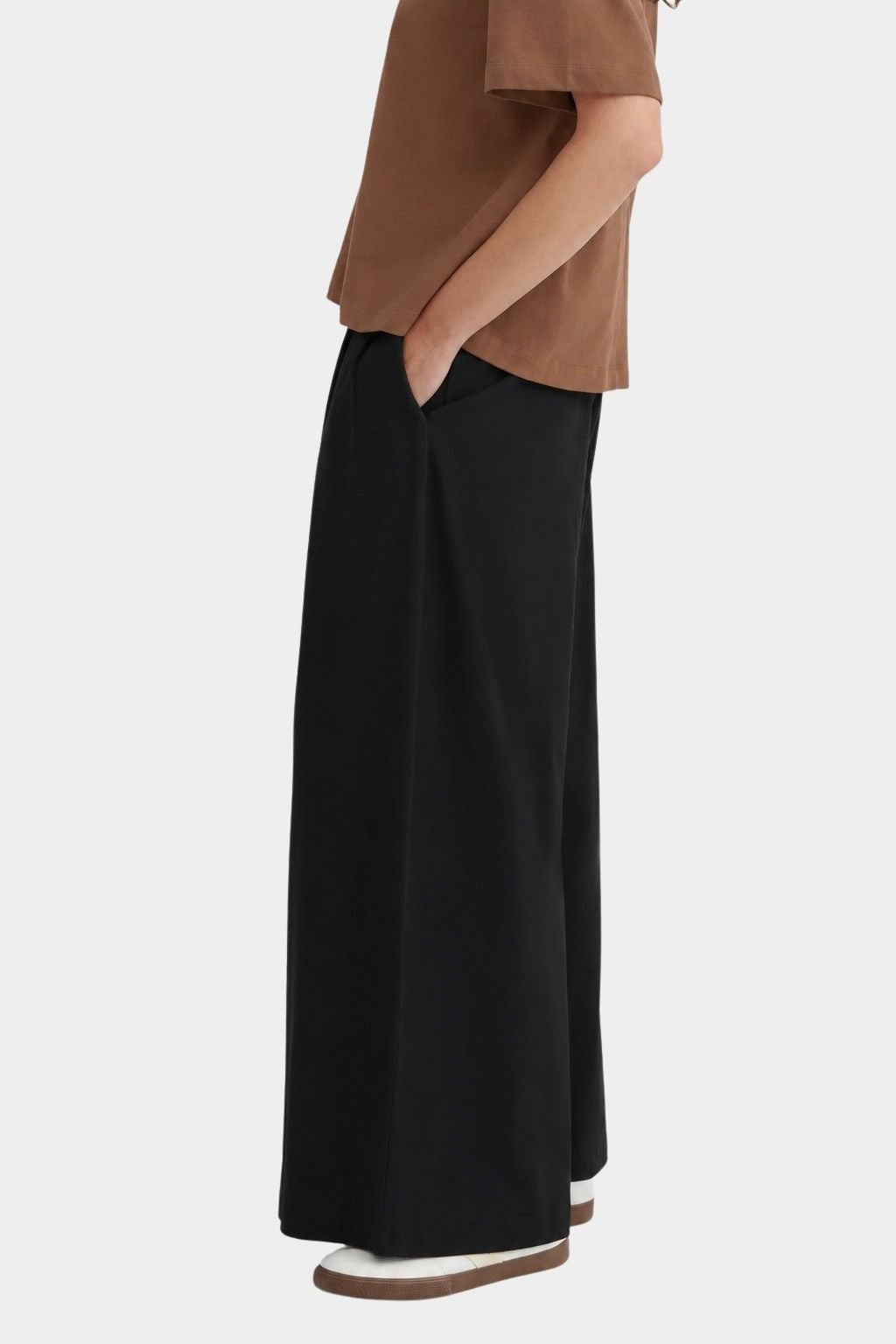 Side view of the black Kowtow Drape Pant showing its wide leg and side seam pocket.