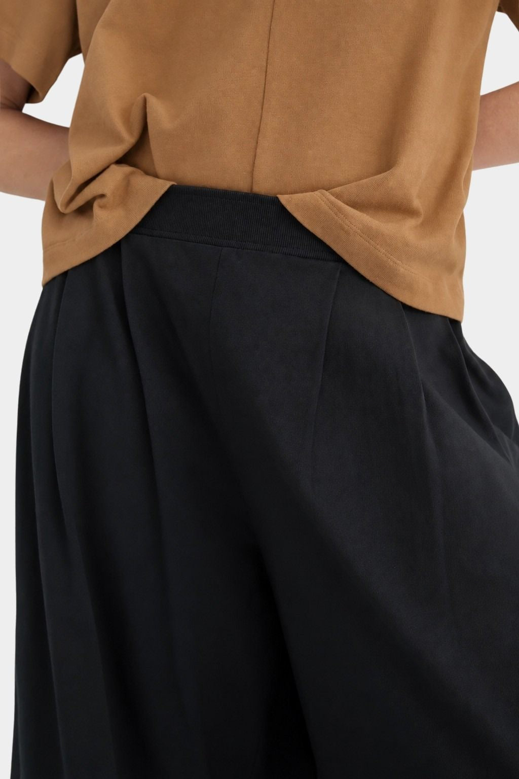 Close view of the black Kowtow Drape Pant showing the ribbed waistband and front pleats.