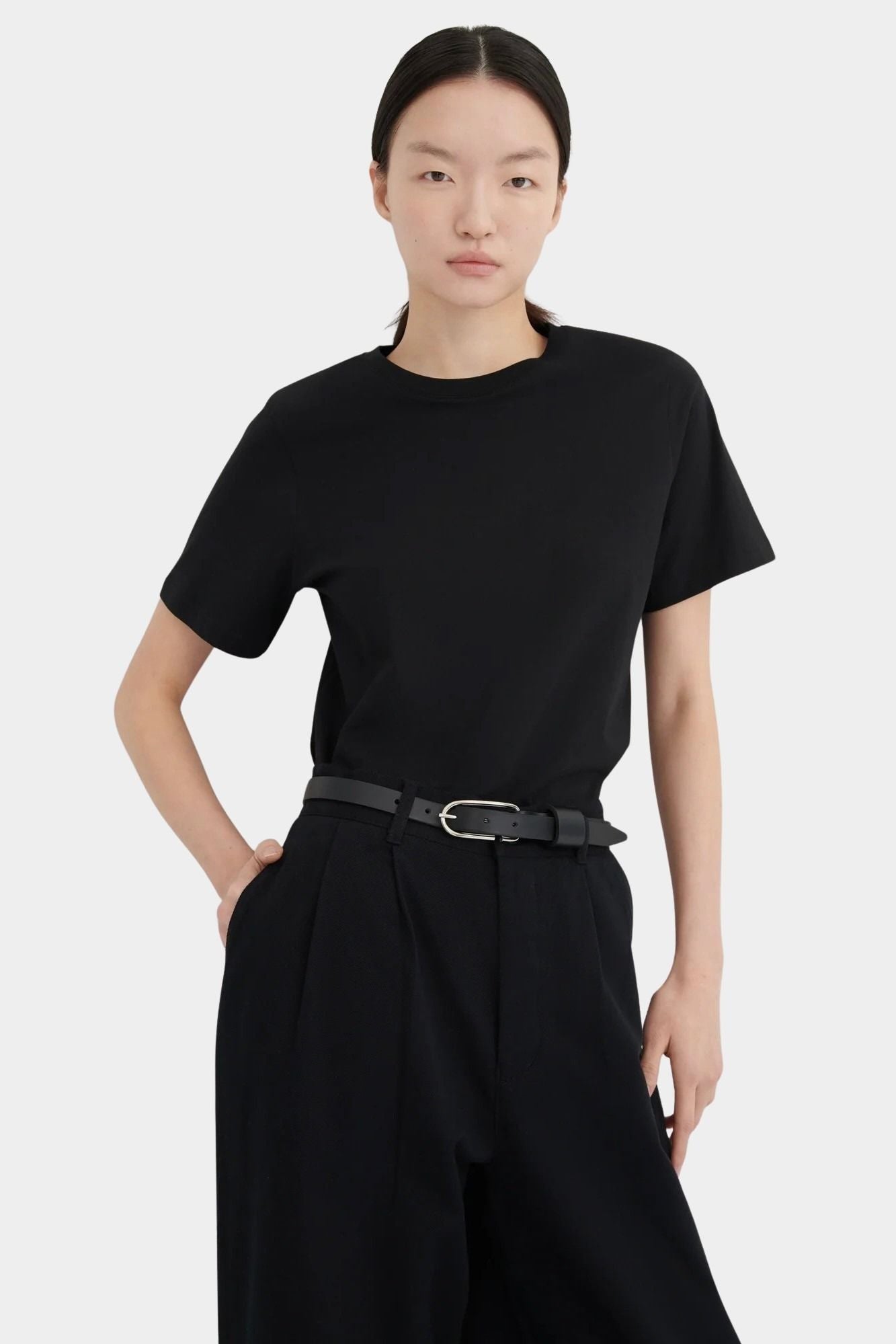 Close front view of the black Kowtow Franz Pant styled with a tucked black tee and belt.