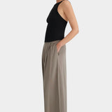 Side view of the cropped black Kowtow Low Back Cami styled with taupe trousers.