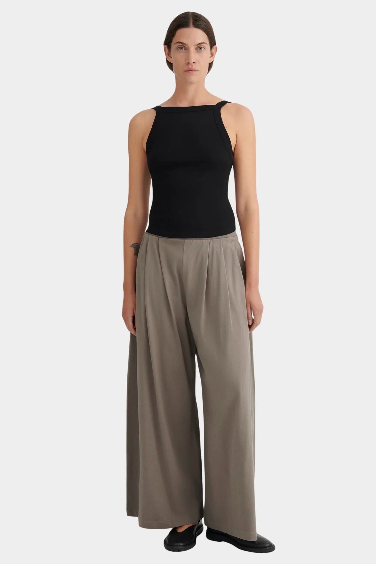 Model wearing the black Kowtow Low Back Cami with taupe wide leg trousers, full front view at YUCCA Denver.