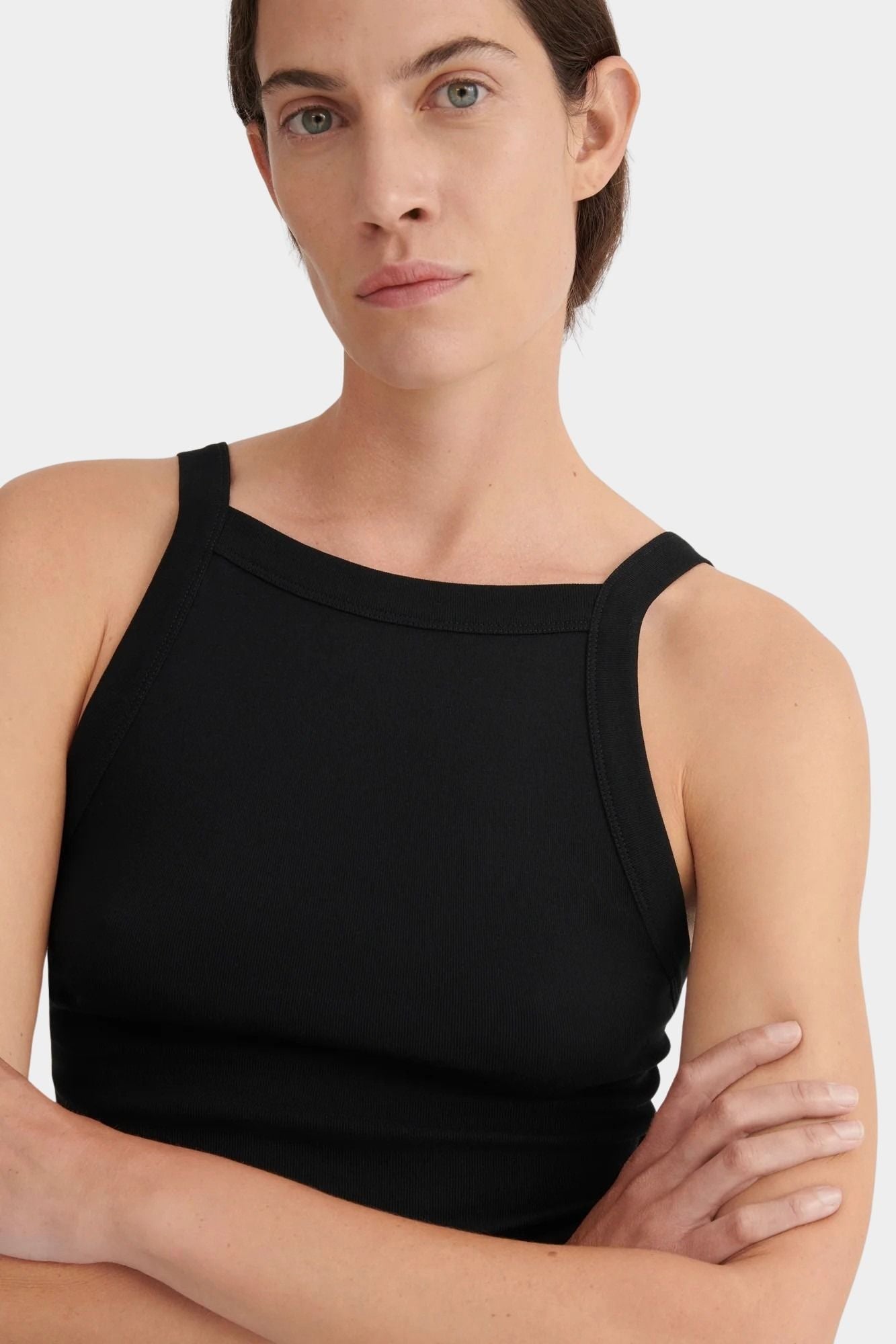 Three-quarter front view of the black Kowtow Low Back Cami showing its close fit and ribbed texture.