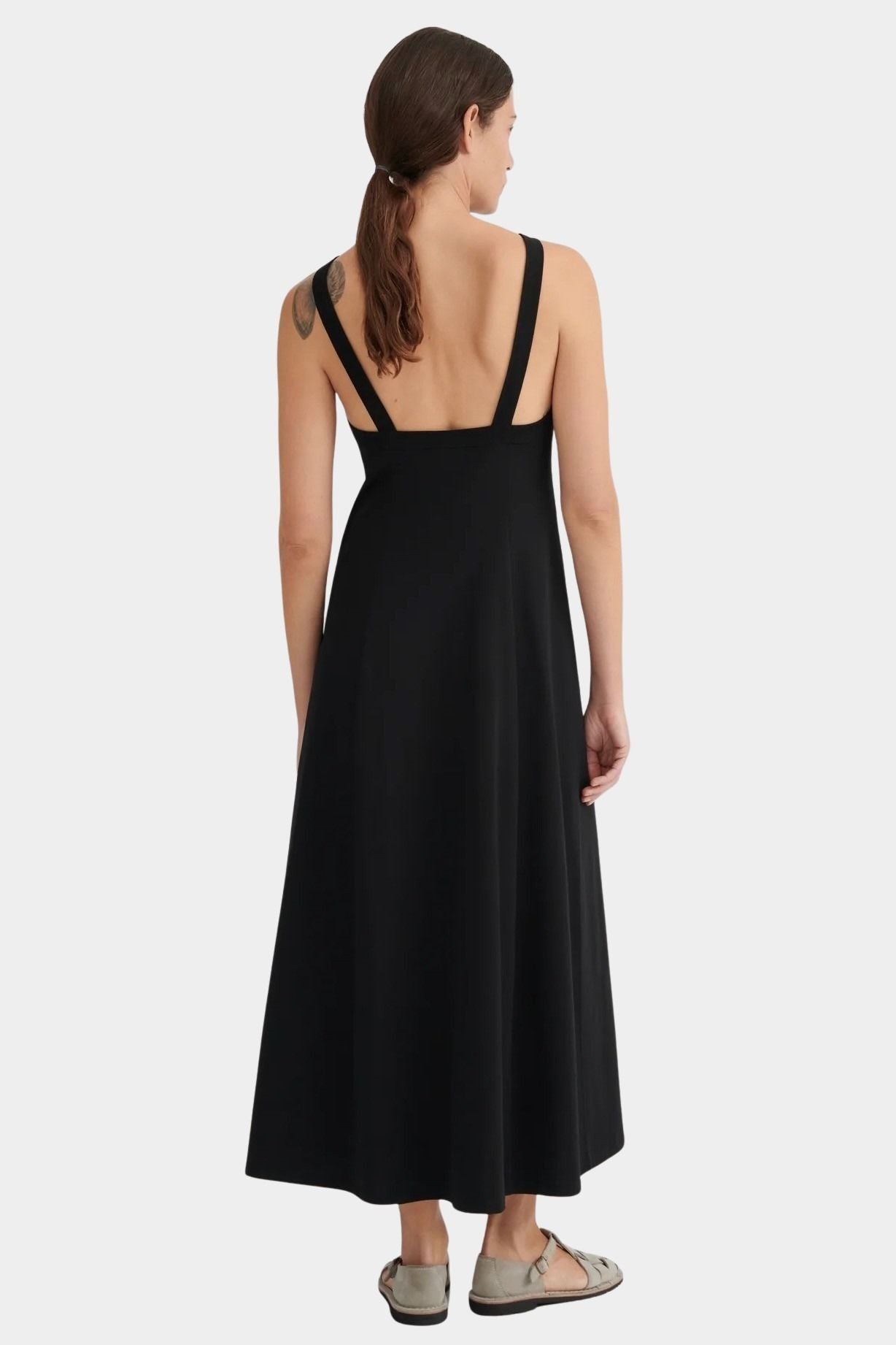 Back view of the black Low Back Dress showing its deep open back, shoulder straps, and flowing skirt