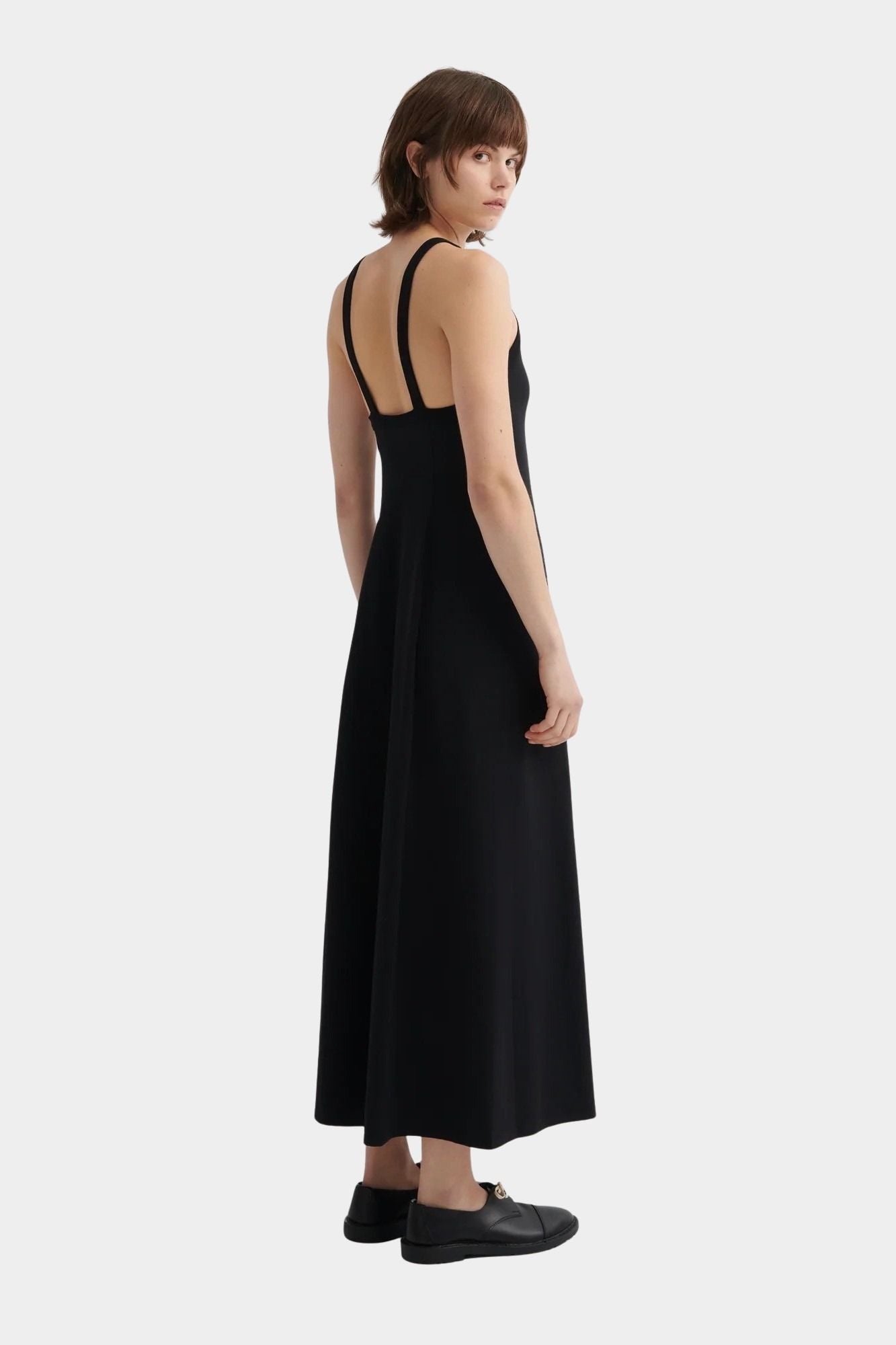 Kowtow Low Back Dress in black worn with black lace up shoes, back view showing low open back