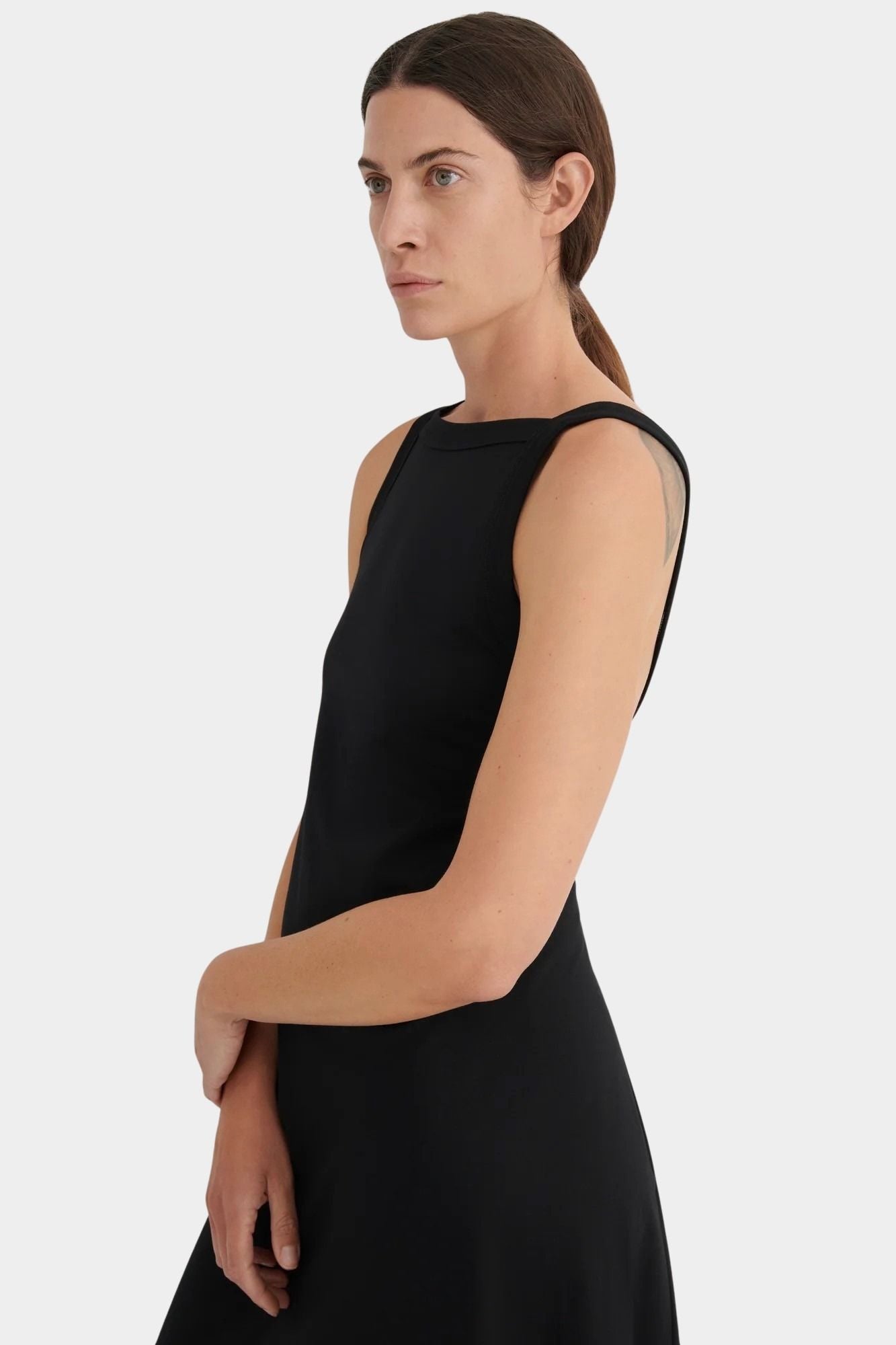 Side detail of the black Kowtow Low Back Dress showing its wide neckline and sleeveless bodice at YUCCA Denver