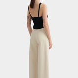 Kowtow Low Back Tank in black worn with cream wide leg trousers, back view