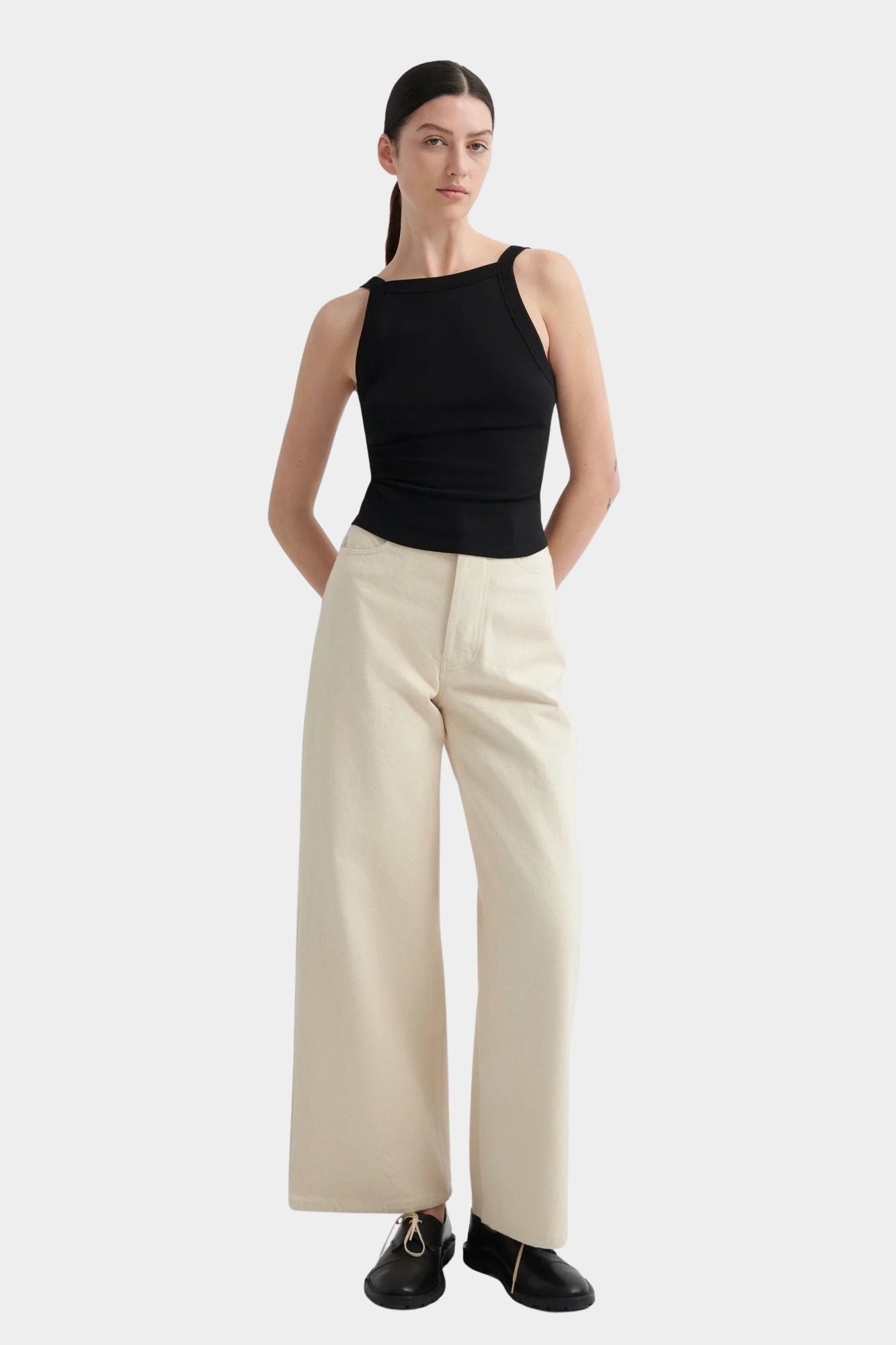 Kowtow Low Back Tank in black worn with cream wide leg trousers, front view