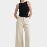 Kowtow Low Back Tank in black worn with cream wide leg trousers, front view