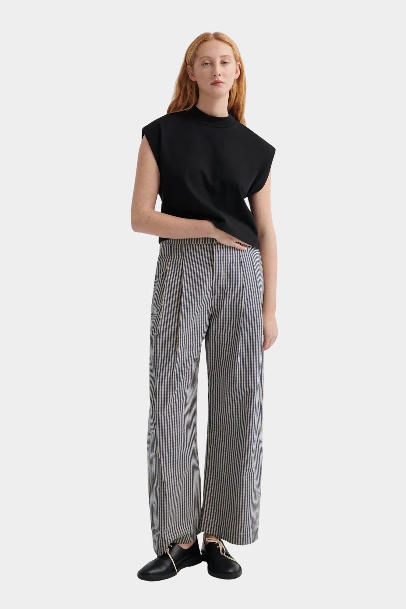 Kowtow Method Tank in black worn with striped wide leg trousers, full length view