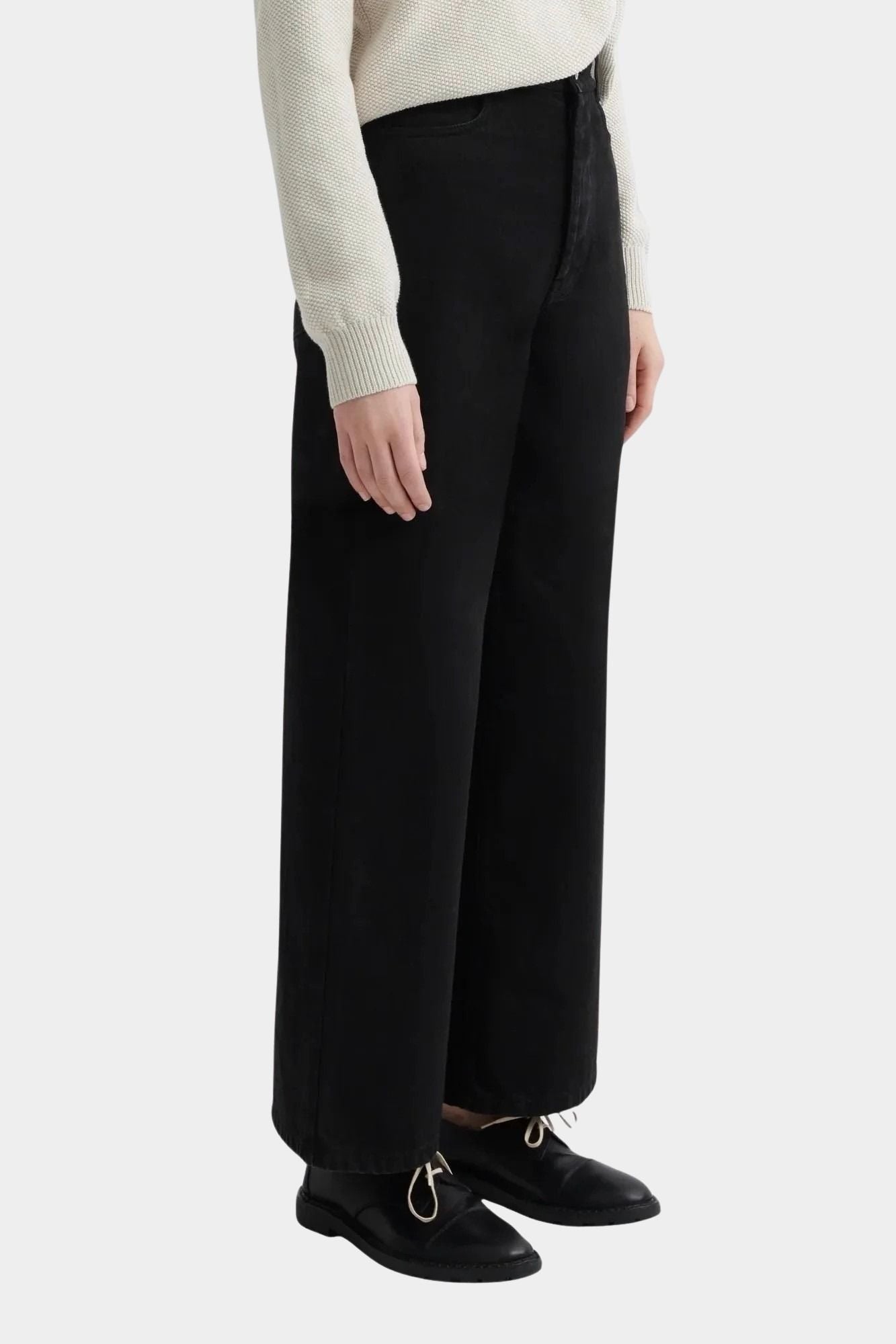Kowtow Sailor Jeans in black worn with cream knit sweater, side view showing wide leg silhouette