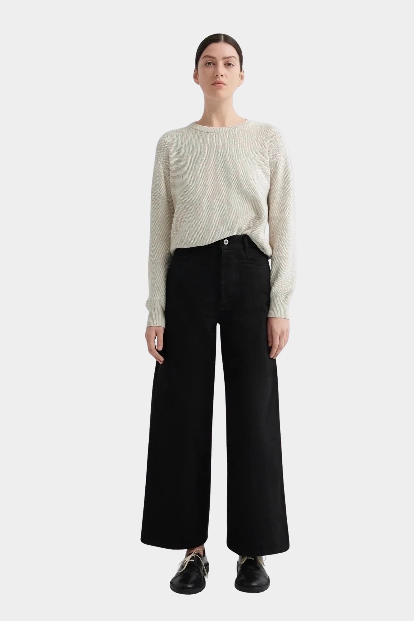 Kowtow Sailor Jeans in black worn with cream knit sweater, full length front view